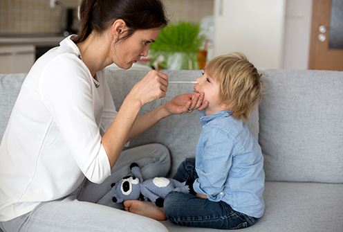 Mother testing her child for covid at home with an Antigen Test to prove a negative result.